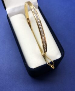 Pulsera rígida de media caña con circonitas de oro montada en oro amarillo de ley 18kts