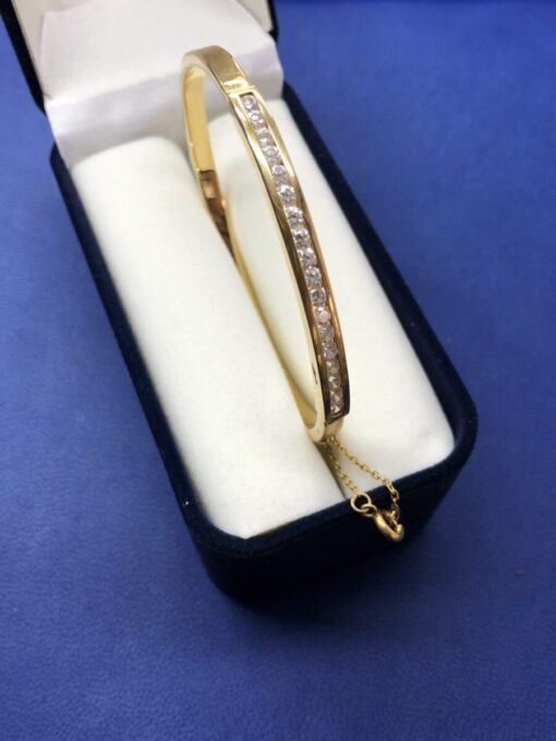 Pulsera rígida de media caña con circonitas de oro montada en oro amarillo de ley 18kts