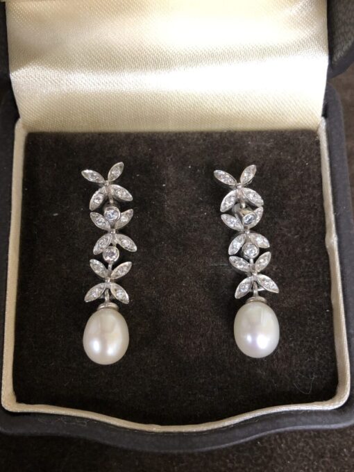 Pendientes forma flor largos con perla cultivada y cuajada de brillantes montados en oro blanco de ley 18kts