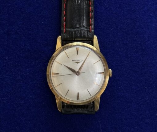 RELOJ LONGINES DE CUERDA. CON PULSERA DE CUERO NEGRO Y DETALLES EN ROJO. EN ORO 18KTS.