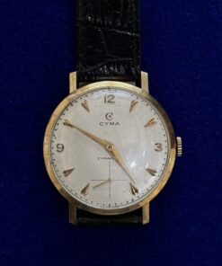 RELOJ CYMA DE CUERDA. CON PULSERA DE CUERO NEGRO. EN ORO 18KTS.
