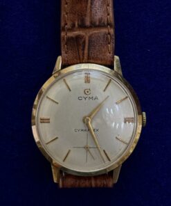 RELOJ  CYMA DE CUERDA MANUAL Y PULSERA DE CUERO MARRÓN, EN ORO 18KTS.