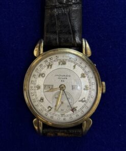 RELOJ MOVADO CON CRONOGRAFO, Y PULSERA DE CUERO NEGRO. EN ORO 18KTS.