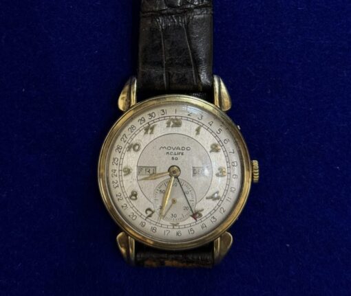 RELOJ MOVADO CON CRONOGRAFO, Y PULSERA DE CUERO NEGRO. EN ORO 18KTS.