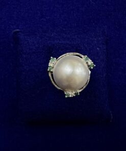 Sortija con perla japonesa central rodeada de brillantes y esmeraldas, montada en oro blanco de ley 18kts.