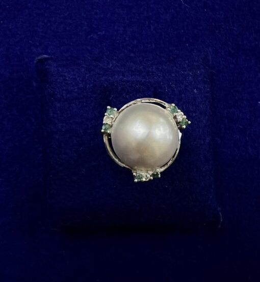 Sortija con perla japonesa central rodeada de brillantes y esmeraldas, montada en oro blanco de ley 18kts.