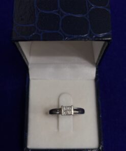 Sortija solitario con cuatro brillantes cuadrados, montado en oro blanco de ley 18kts.