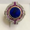 Sortija circular Art Decó con lapislázuli central en doble orla de rubíes y diamantes, en oro amarillo de ley 18 kts.