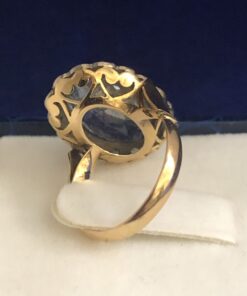 Alternative view of Sortija con piedra azul y orla de diamantes con vistas en plateado en oro de ley 18 kts, presenta calado con motivos de corazón en la parte trasera