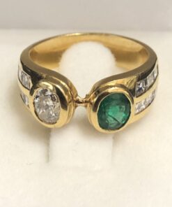 Alternative view of Sortija tipo "tú y yo" en oro de ley 18 kts, con esmeralda de 0'70 cts y brillante de 0'70 cts acompañados de dos filas de brillantes en carré en cada brazo.