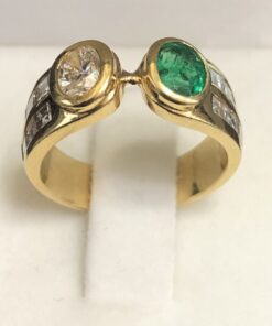Sortija tipo "tú y yo" en oro de ley 18 kts, con esmeralda de 0'70 cts y brillante de 0'70 cts acompañados de dos filas de brillantes en carré en cada brazo.