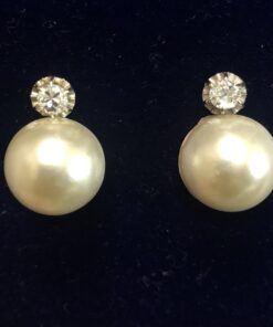 Pendientes "tú y yo" con medias perlas japonesas y brillantes de 0'20 cts cada uno montados en garra ilusión, oro de ley 18 kts.