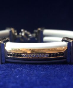 Pulsera marca BARAKA, de caucho color blanco, con placa de oro con incrustaciones de brillantes y zafiros, y eslabones de oro bicolor 18 kts.