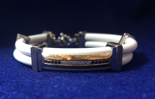 Pulsera marca BARAKA, de caucho color blanco, con placa de oro con incrustaciones de brillantes y zafiros, y eslabones de oro bicolor 18 kts.