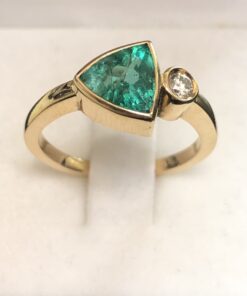 Sortija con esmeralda en bisel talla triangular y un brillante engastado en bisel montados en oro amarillo de ley 18 kts.
