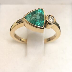 Sortija con esmeralda en bisel talla triangular y un brillante engastado en bisel montados en oro amarillo de ley 18 kts.