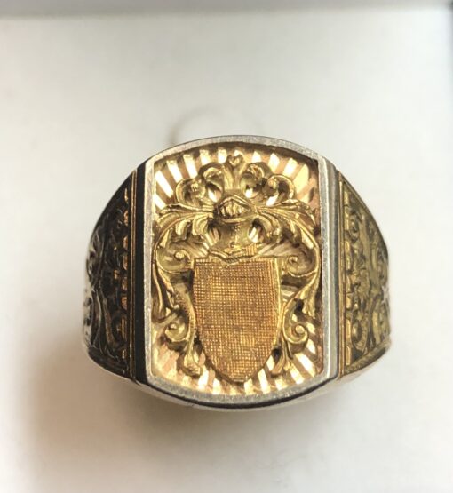 Sello de caballero con escudo heráldico en relieve y motivos de roleos en los laterales, en oro amarillo de ley 18 kts.