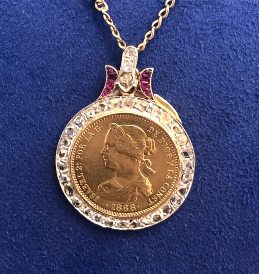 Colgante con moneda de oro de 21 kts de 10 escudos de Isabel II, año 1868, montada en una orla de diamantes y rubíes en oro de ley 18 kts.