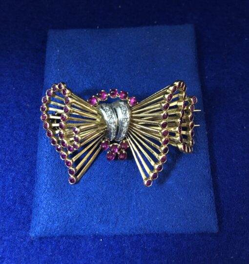Broche retro en forma de lazada con con 0'12 cts de brillantes y rubíes reconstituidos en oro amarillo de ley 18 kts.