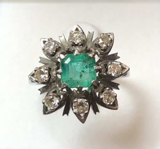 Sortija en forma de flor con auténtica esmeralda colombiana y 0'55 cts de brillantes en oro blanco de ley 18 kts.