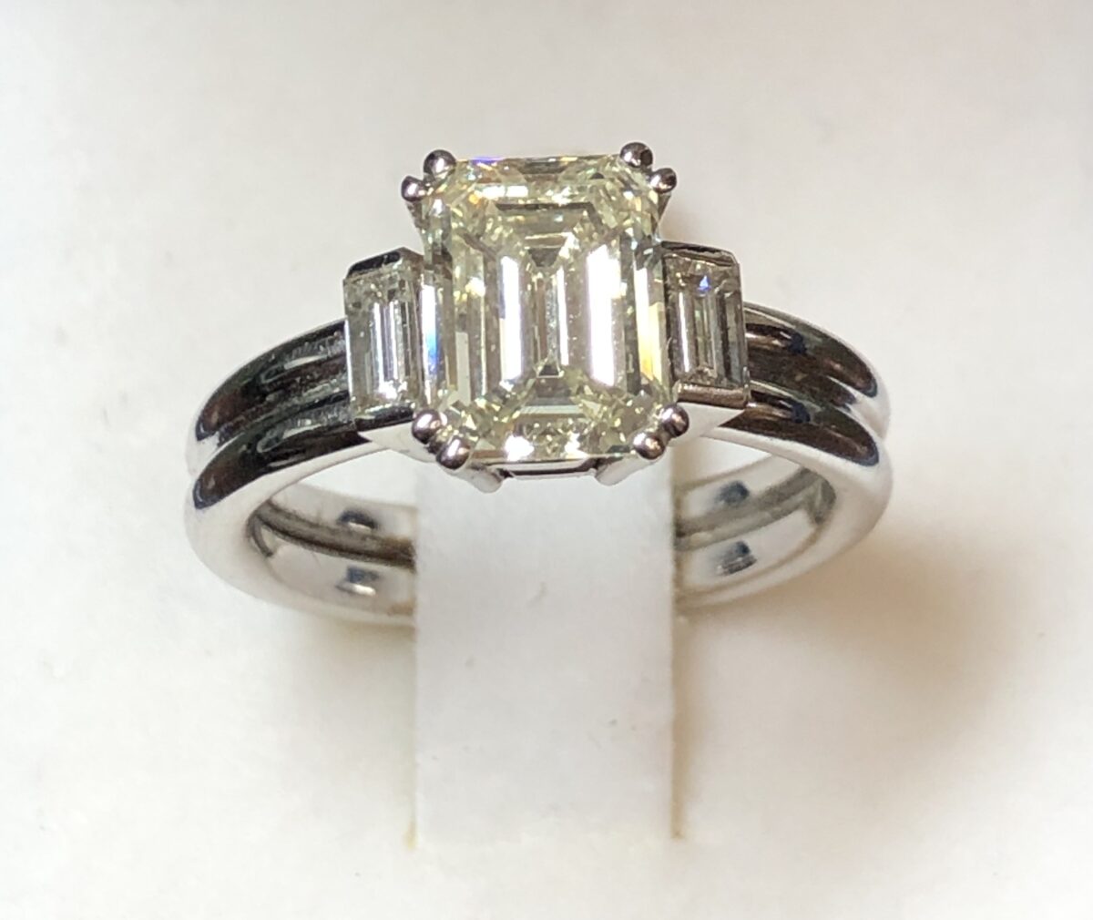 Tresillo con diamantes laterales talla baguette, (color HVS1) de 0'48 cts en total, y diamante central talla esmeralda (color K VS1) de 2'17 cts en oro blanco de ley 18 cts.