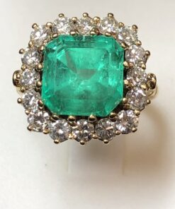 Sortija en forma de rosetón con auténtica esmeralda colombiana de 4 cts y orla de brillantes color H de 1'70 cts en total, montados en oro amarillo de ley 18 kts.
