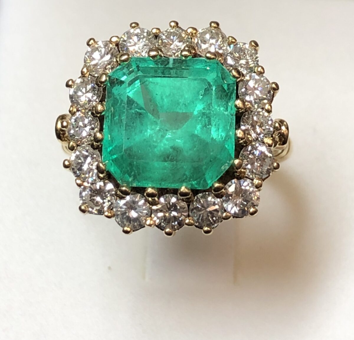 Sortija en forma de rosetón con auténtica esmeralda colombiana de 4 cts y orla de brillantes color H de 1'70 cts en total, montados en oro amarillo de ley 18 kts.