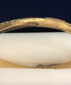 Brazalete rígido de media caña con motivos cincelados en oro amarillo de ley 18 kts.