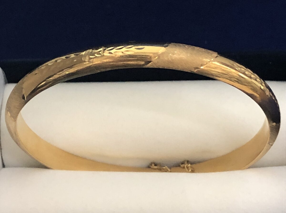 Brazalete rígido de media caña con motivos cincelados en oro amarillo de ley 18 kts.