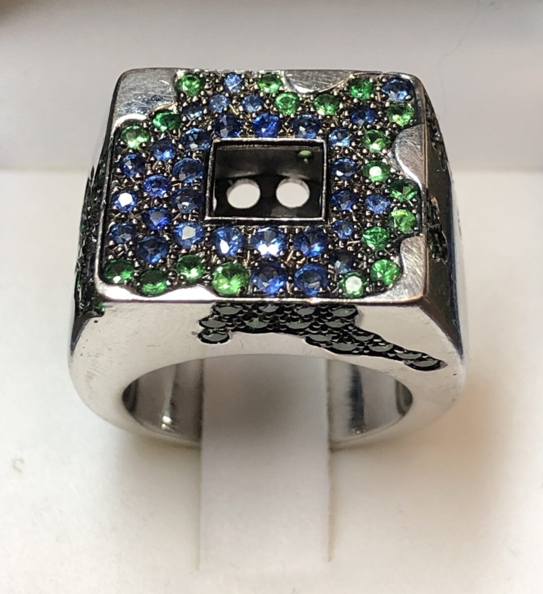 Sortija con diseño moderno de Mercedes Llop de Villalonga (firmado), con pavé de zafiros y granates tsavoritas montados en oro blanco de ley 18 kts.