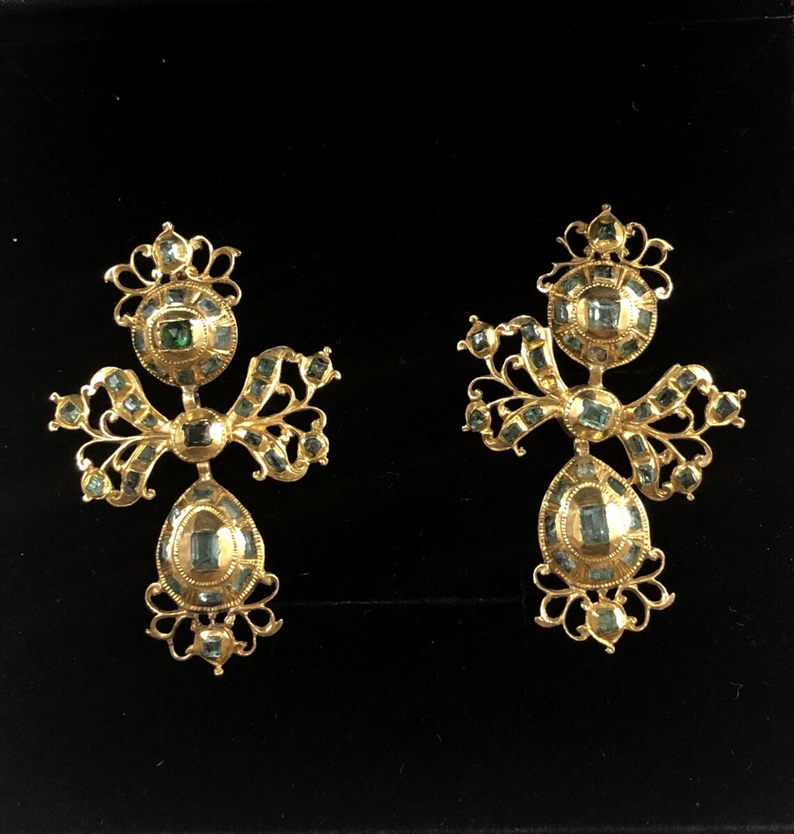 Pendientes populares del siglo XVIII-XIX, de tres cuerpos: botón, lazo y perilla colgante, cuajados de esmeraldas y adornos de filigrana.