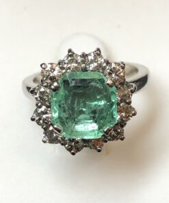 Sortija en forma de rosetón con esmeralda central de 2'10 cts y orla de brillantes de 0'60 cts en total, realizada en oro blanco de ley 18 kts