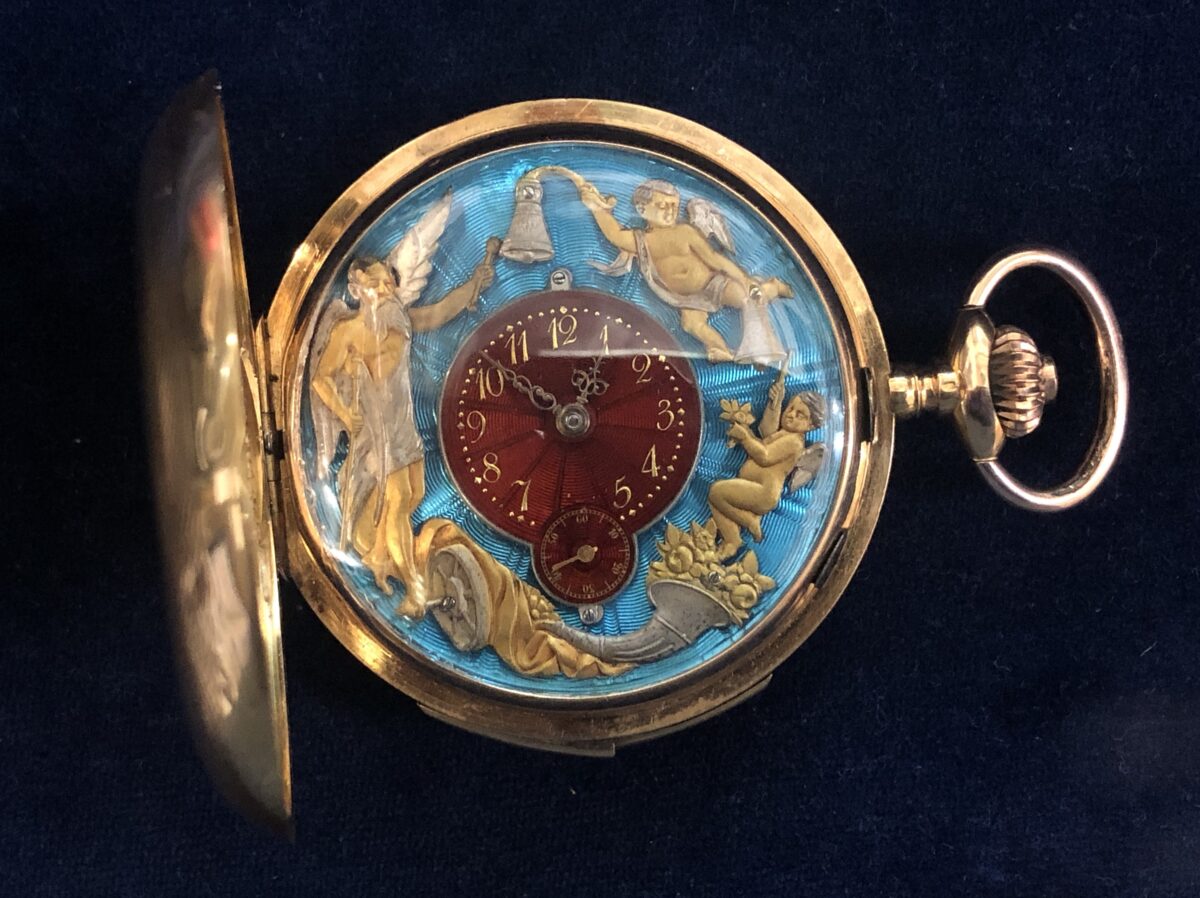 Reloj de bolsillo con cronógrafo, su interior cuenta con motivos en forma de cornucopia y ángeles autómatas con mecanismo de repetición en las campanadas, esmaltado en guilloché de colores azul y rojo