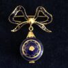 Precioso broche de principios del siglo XX en forma de lazada con esmalte azul, con un pequeño reloj Monvis de 17 joyas en pendentif, realizado en oro amarillo de ley 18 kts.