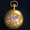 Pequeño reloj de bolsillo con motivos florales en esmalte al fuego policromado y detalles en diamantes, con agujas Luis XVI, con 10 rubíes en el movimiento, realizado en oro de ley 18 kts