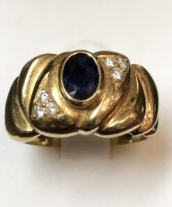 Sortija ancha vintage (años 80) con zafiro central de 0'50 cts y 0'12 cts de brillantes en total, realizada en oro amarillo de ley 18 kts.