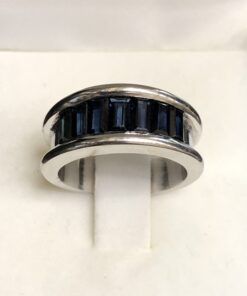 Sortija ancha tipo media alianza con zafiros calibrados en oro blanco de ley 18 kts.