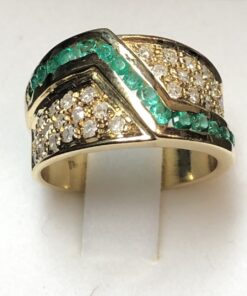 Sortija ancha con greca de 0'32 cts de esmeraldas y enriquecida con 0'80 cts de brillantes a los laterales, realizada en oro amarillo de ley 18 kts.