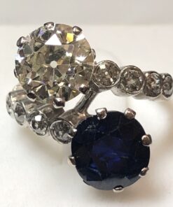 Sortija "tú y yo" con brillante principal de 2'60 cts, color K-VS1, zafiro de 2'80 cts y brillantes laterales de 0'42 cts en total, realizado en oro blanco de ley 18 kts.