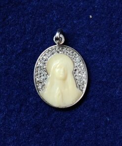 Medalla modernista de ppos. del siglo XX, realizada con retrato de la Virgen tallado en hueso y cuajada con 0'40 cts de brillantes en oro blanco de ley 18 kts. Firmada por el escultor francés F. Vernon