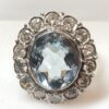 Sortija vintage en forma de rosetón con topacio azul central y orla de 1'40 cts de brillantes, realizada en oro blanco de ley 18 kts.