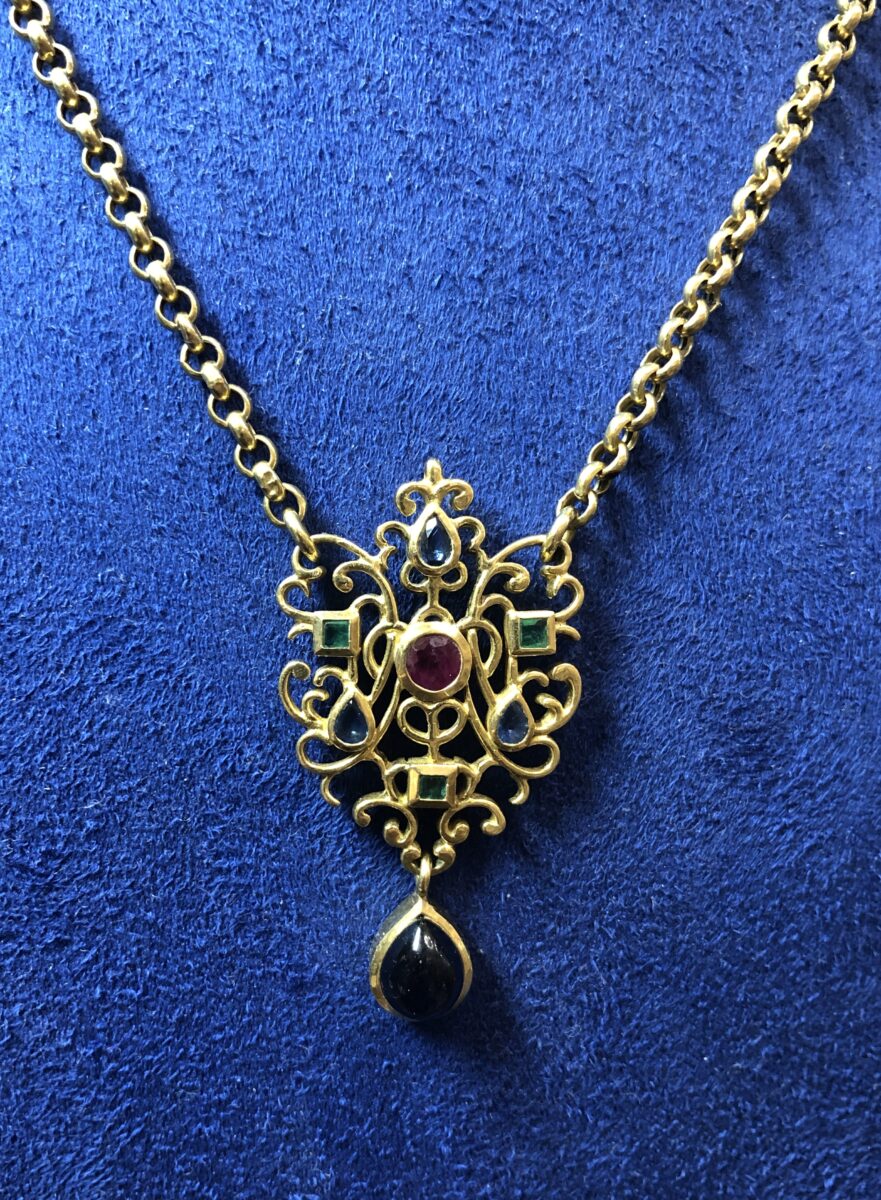 Gargantilla vintage de rolos con colgante de motivos orgánicos con zafiros, rubíes y esmeraldas realizada en oro amarillo de ley 18 kts.