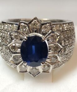 Sortija ancha con zafiro central de 2 cts en rosetón, enriquecida con 1'76 cts de brillantes, realizada en oro blanco de ley 18 kts.