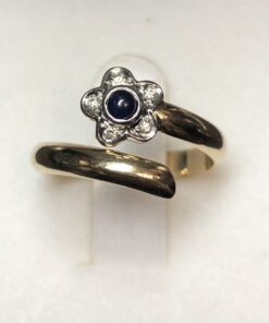 Sortija en forma de espiral con flor aderezada con brillantes y centro de zafiro natural, realizada en oro blanco y amarillo de ley 18 kts.