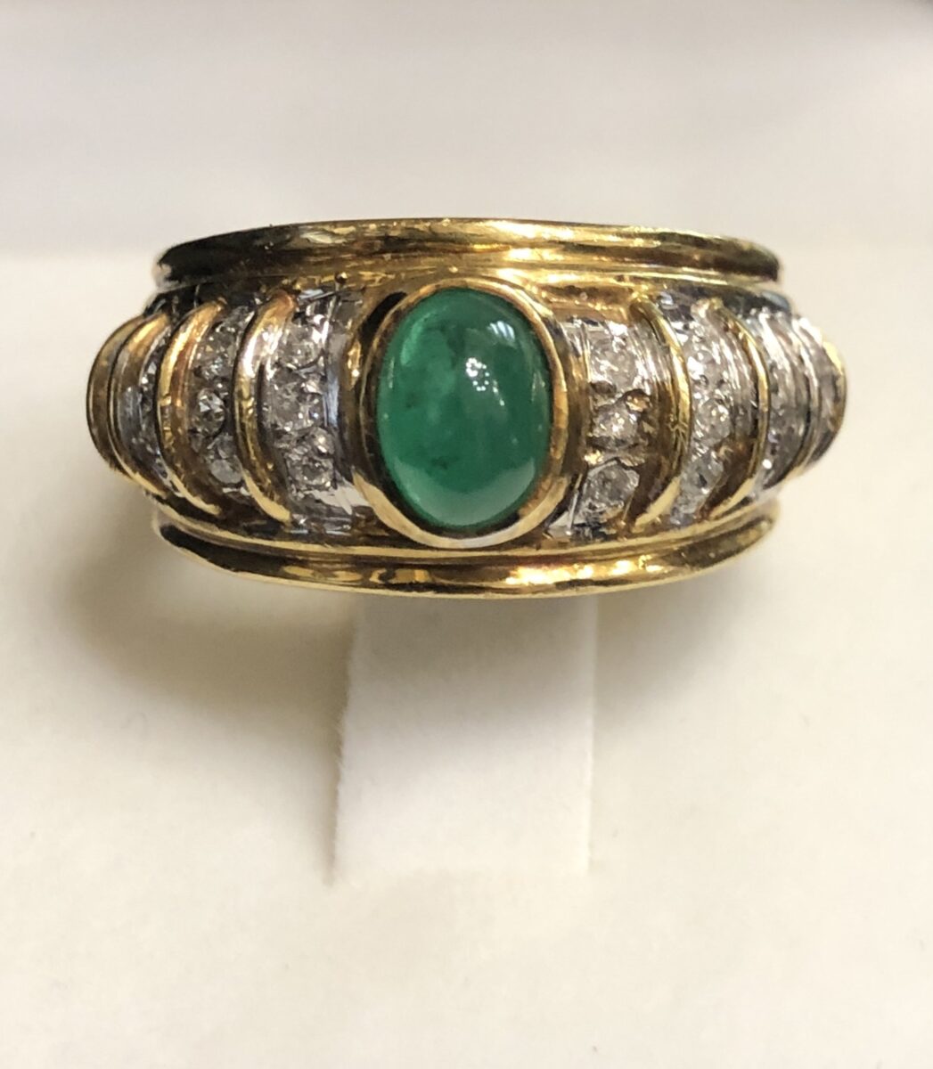Sortija bombé con esmeralda central en cabujón y gallones enriquecidos con diamantes, realizada en oro amarillo de ley 18 kts.