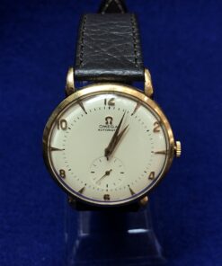 Reloj Omega vintage con cronógrafo, realizado en oro de ley 18 kts, automático con mecanismo de martillo, correa negra de piel genuina