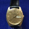 Reloj Omega vintage de esfera dorada con día y fecha, realizado en oro de ley 18 kts, automático, con correa negra de piel genuina