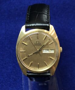 Reloj Omega vintage de esfera dorada con día y fecha, realizado en oro de ley 18 kts, automático, con correa negra de piel genuina