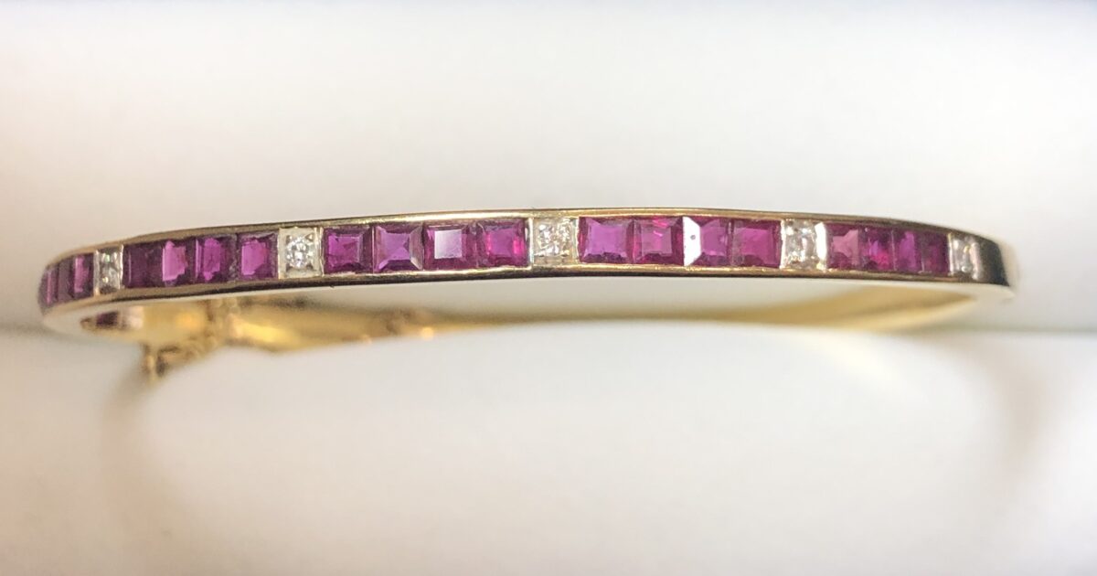 Pulsera de media caña con rubíes en carre y 0'14 cts de brillantes, realizada en oro amarillo de ley 18 kts.