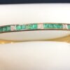 Pulsera de media caña con esmeraldas en carre y 0'14 cts de brillantes, realizada en oro amarillo de ley 18 kts.
